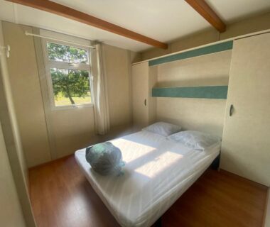 Chambre avec lit double et fenêtre donnant sur jardin dans les chalets d'Uza