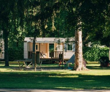 Mobil-home installé sous grands arbres sur pelouse au Camping intercommunal de Beaurepaire