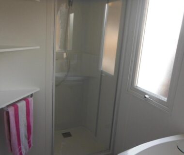 Salle de bain avec cabine de douche et serviette rayée au Camping l'Eléphant
