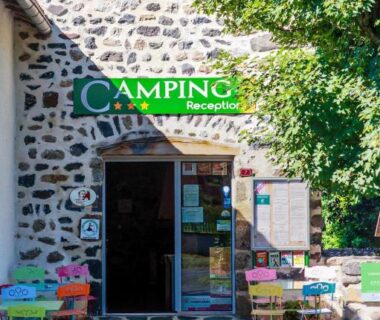 Façade en pierre avec chaises colorées à l'accueil du camping l'Estela sur le GR70