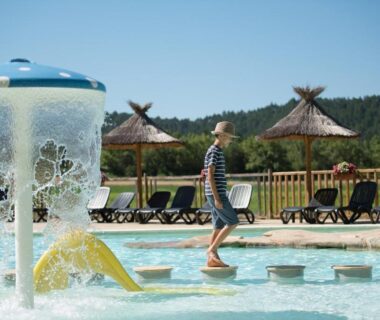 Bassin ludique avec enfant sur plots et parasols au Camping l'Hirondelle Drôme