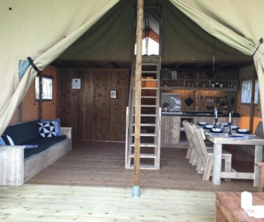 Intérieur de tente lodge avec coin cuisine et table à manger au Camping l'Hirondelle Drôme