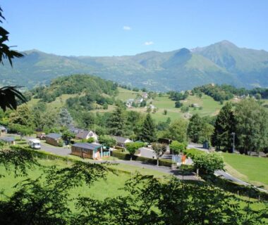 Vallée verte et maisons avec montagnes en arrière-plan au Camping l'Ideal