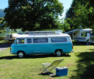 Emplacement herbeux avec van turquoise et caravanes au Camping l'Ideal