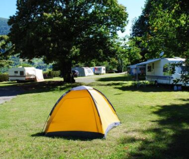 Prairie ombragée avec tente et caravanes au Camping l'Ideal