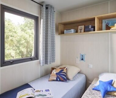 Chambre avec deux lits et fenêtre dans le mobil-home du Camping l'Oso