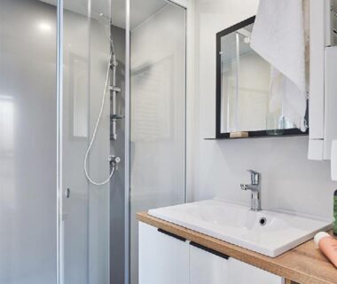 Salle de bains avec cabine de douche en verre lavabo et miroir du Camping l'Oso