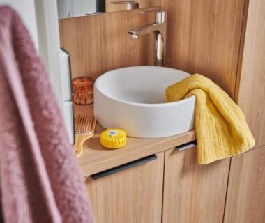 Salle de bain avec lavabo vasque blanc sur meuble en bois et serviette jaune au Camping l'Oso