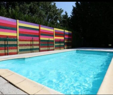Piscine extérieure bordée d'une clôture rayée au Camping la Chaumière