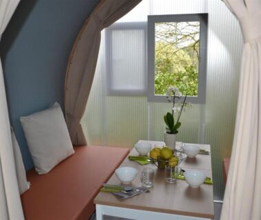 Coin repas lumineux avec table vaisselle et orchidée au Camping la Chaumière
