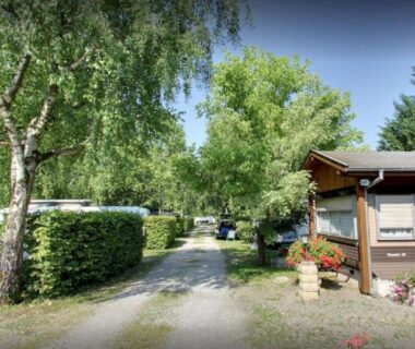 Allée centrale bordée de haies et d'arbres avec kiosque d'accueil au Camping la Chaumière