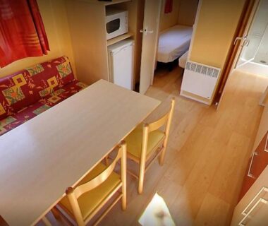 Intérieur mobil-home coin repas banquette et kitchenette du Camping la Chaumière