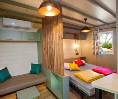 Intérieur mobil-home avec lits et coin salon au Camping la Croix du Sud
