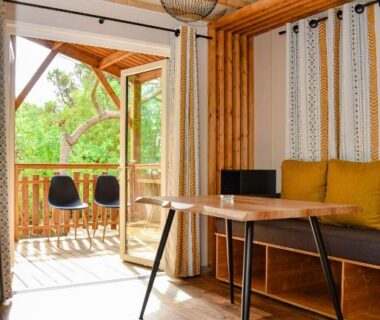 Salon intérieur avec bureau et terrasse en bois au Camping la Croix du Sud