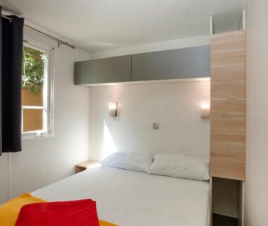 Chambre avec lit double et fenêtre au Camping la Croix du Sud
