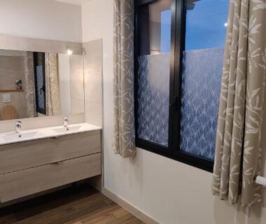 Salle de bain avec lavabo miroir et fenêtre du Camping la Haie Penée