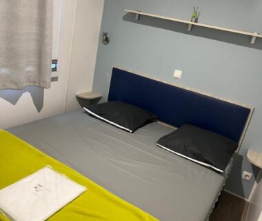 Chambre avec lit double couverture et serviette pliée au Camping la Marine