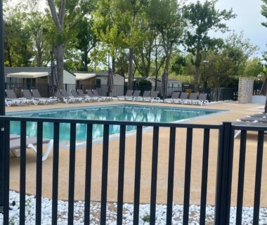 Bord de piscine clôturé avec transats au Camping la Marine