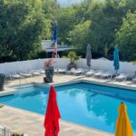 Piscine extérieure entourée de transats et parasols au Camping la Paoute