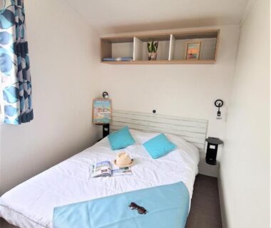 Chambre double avec lit coussins et étagères dans le mobil-home du Camping la Plage