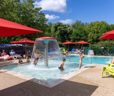 Piscine avec pataugeoire et parasols rouges au Camping la Plage Lot Vallée de la Dordogne Rocamadour