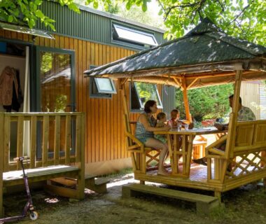 Terrasse couverte avec table et convives au Camping la Plage Lot Vallée de la Dordogne Rocamadour