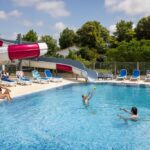 Piscine extérieure avec toboggan et transats au Camping la Prairie