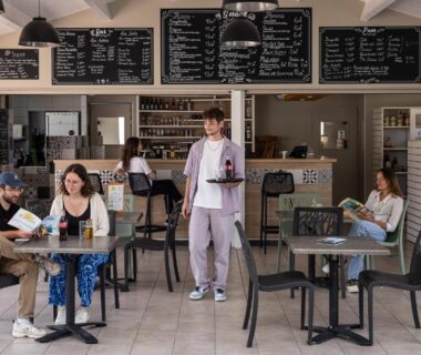 Café intérieur avec clients et serveur au Camping la Prairie