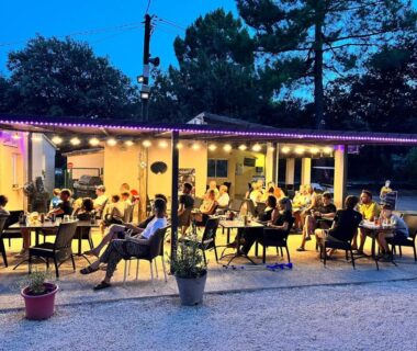 Terrasse extérieure avec tables et convives au Camping la Simioune