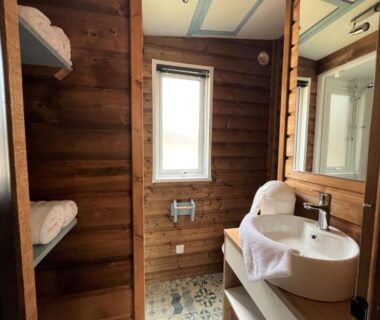 Salle de bains en bois avec lavabo et lits superposés au Camping la Tamarissière