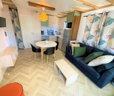 Séjour avec canapé et coin repas dans le mobil-home du Camping la Tamarissière