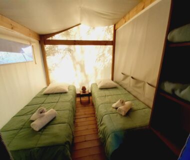 Intérieur de tente avec deux lits et serviettes au Camping la Venise Verte