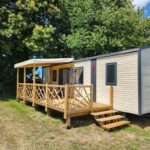 Emplacement herbeux avec mobil-home et terrasse en bois au Camping le Balcon de la Baie