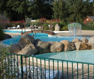 Piscine extérieure avec bassins et rochers au Camping le Balcon de la Baie