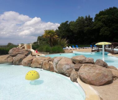 Piscine extérieure avec lagon et rochers au Camping le Balcon de la Baie