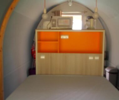 Cabine avec lit et meuble orange sous voûte au Camping le Bois Jahan