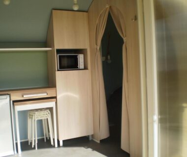Intérieur kitchenette avec micro-ondes et tabourets au Camping le Bois Jahan