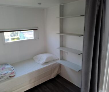 Chambre avec lit simple et étagères dans le Camping le Bois Jahan
