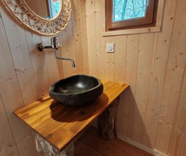 Salle de bains avec lavabo en pierre sur plan en bois au Camping le Colorado