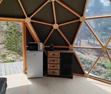 Intérieur de dôme avec kitchenette et vue sur forêt au Camping le Colorado
