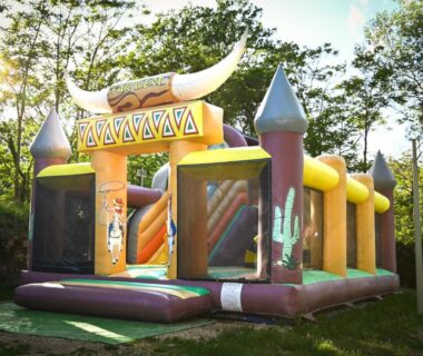 Aire de jeux extérieure avec château gonflable et toboggan au Camping le Colorado