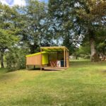 Clairière herbeuse et petit chalet en bois dans le Camping le Convivial Cop'Camp 2 personnes