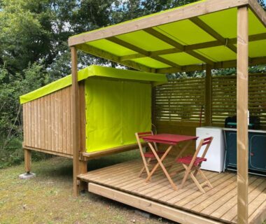 Terrasse couverte en bois avec table pliante et mini frigo du Camping le Convivial Cop'Camp 2 personnes