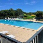 Piscine extérieure avec toboggan et transats au Camping le Convivial Mobil home 3 chambres