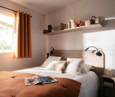 Chambre avec lit double fenêtre et lampes de lecture au Camping le Dolmen