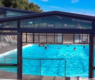 Piscine couverte sous verrière avec baigneurs au Camping le Dolmen