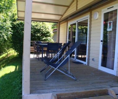 Terrasse couverte avec transats et salon de jardin sur pelouse du Camping le Grand Cerf