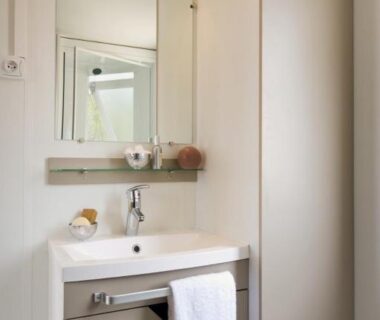 Salle de bain avec lavabo et miroir au Camping le Mas des Sedaries