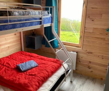 Cabine en bois avec lits superposés et fenêtre au Camping le Montbartoux
