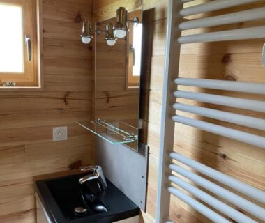 Intérieur de salle de bains en bois avec lavabo et radiateur sèche-serviettes au Camping le Montbartoux